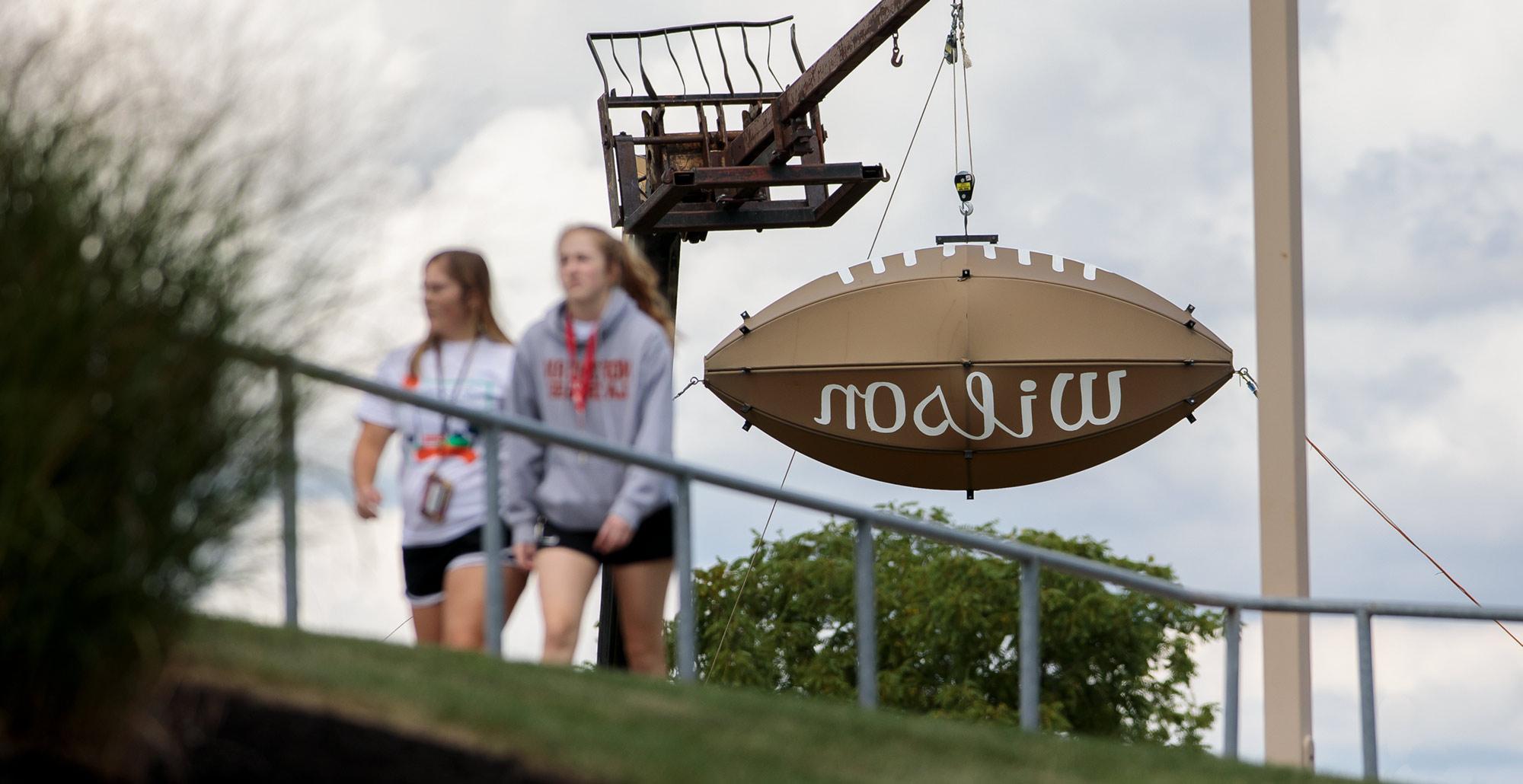 学生们走过俄亥俄州北部大学校园dial - robertson体育场外的巨型威尔逊足球.